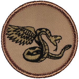 May include: A brown embroidered patch with a black winged rattlesnake design. The snake is coiled and has its fangs bared.