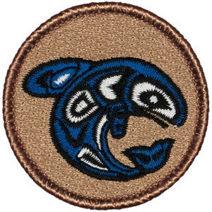 May include: A round, brown embroidered patch with a blue and white stylized salmon design. The salmon is facing right and has a white eye.