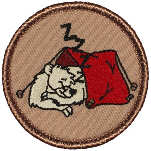 May include: A brown embroidered patch with a white animal sleeping in a red tent. The tent has a 'Z' on top of it.