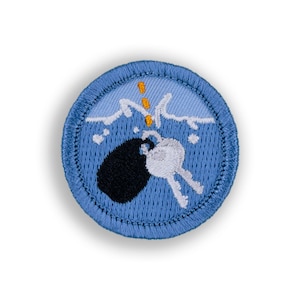 May include: A blue embroidered patch with a white and black bomb sinking into the water with orange bubbles coming up.
