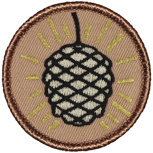 May include: A brown embroidered patch with a tan background featuring a black and white pine cone with gold rays around it.