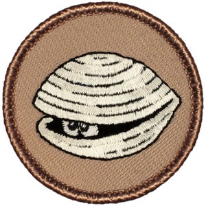 May include: A brown embroidered patch with a white clam shell design. The clam shell is closed and has a detailed texture.