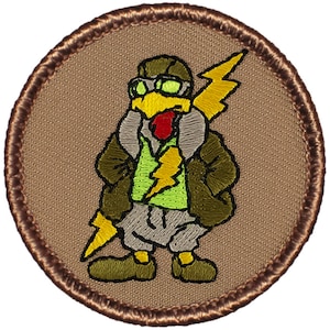 May include: A brown embroidered patch with a cartoon turkey wearing a brown leather jacket, green shirt, and goggles. The turkey is holding a yellow lightning bolt.