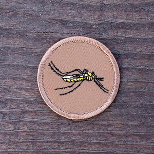 May include: A brown embroidered patch with a black and yellow mosquito design.