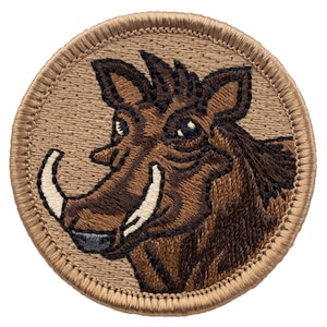 May include: Embroidered patch featuring a brown warthog with large tusks. The patch is circular and has a tan background with a brown stitched border.