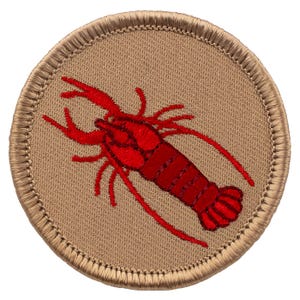 May include: A red embroidered lobster on a tan circular patch with a brown stitched border.