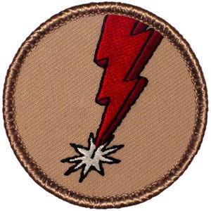 May include: Embroidered patch featuring a red lightning bolt striking a white starburst against a tan background. The patch has a brown stitched border, suitable for jackets, bags, or other fabric items.