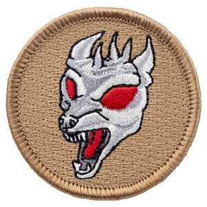 May include: A round, tan embroidered patch with a white and red embroidered image of a snarling, demonic creature with red eyes.