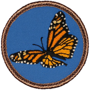May include: A brown embroidered patch with a blue background featuring a monarch butterfly with orange and black wings.