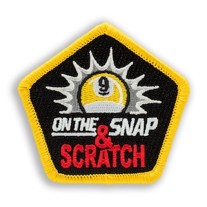 May include: A yellow and white embroidered patch with a black background. The patch features a pool ball with the number 9 on it, surrounded by a sunburst design. The text "On the Snap & Scratch" is written in white and red letters.