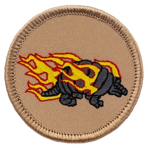 May include: A round, tan embroidered patch with a gray and yellow cartoon armadillo on fire. The armadillo is facing right and has a yellow flame coming out of its back.
