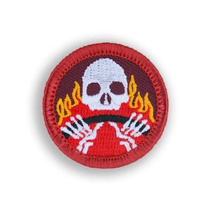 May include: Red, white, and orange embroidered patch with a skull in flames and skeletal hands holding a black bar.