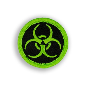 May include: Round black patch with a neon green biohazard symbol. The symbol is centered on the patch and is surrounded by a neon green border. The patch is likely an iron-on or sew-on patch.