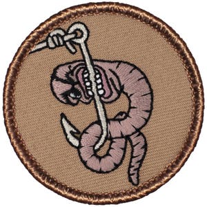 May include: A brown embroidered patch with a white hook and a pink worm with a face on it. The worm is on the hook and has a distressed look on its face.