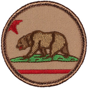 May include: A brown embroidered patch with the California state flag. The flag features a brown bear walking on green grass, a red star, and a red stripe.