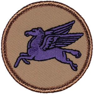 May include: A circular patch featuring a purple Pegasus, a mythical winged horse, in mid-flight. The Pegasus is embroidered on a tan background, with a brown stitched border. The design is detailed and eye-catching.