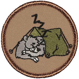 May include: A brown embroidered patch with a gray koala sleeping in a green tent. The tent has a Z on top of it.