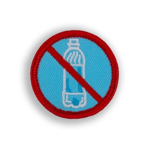 May include: A red and blue embroidered patch with a white outline of a bottle with a red diagonal line through it. The patch is a no plastic bottle symbol.