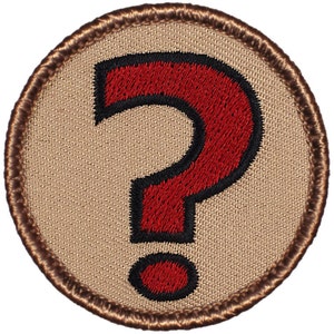 May include: A brown and tan embroidered patch with a red question mark in the center. The question mark is outlined in black.
