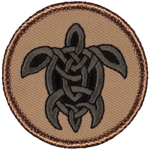 May include: A brown and black embroidered patch featuring a Celtic knot design in the shape of a sea turtle. The patch has a brown border.