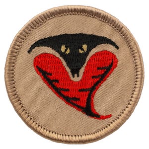 May include: A round, tan-colored patch with a black and red embroidered snake design. The snake is coiled with its head facing forward and its mouth open. The snake's eyes are yellow.