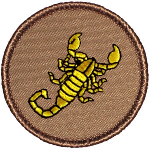 May include: A brown embroidered patch with a yellow scorpion design. The scorpion is facing right and has a curled tail.