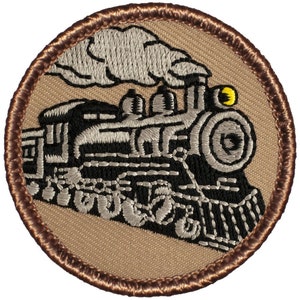 May include: A brown embroidered patch with a black and white steam engine train with a gray smoke plume. The train has a yellow headlight and is on a gray track.