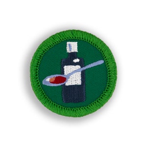 May include: Green embroidered patch with a white bottle and a blue spoon with red liquid. The bottle has a white label and a white cap.