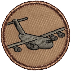 May include: A brown embroidered patch with a gray airplane on a tan background. The airplane is facing right and has a brown outline.