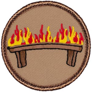 May include: A brown embroidered patch with a campfire on a wooden platform. The flames are red and yellow.