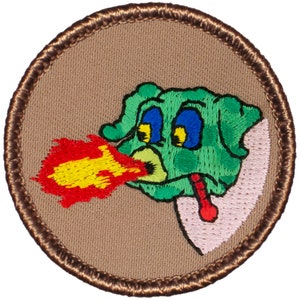 May include: A brown embroidered patch with a green cartoon dragon blowing fire. The dragon has yellow eyes and blue pupils. The fire is red and yellow.