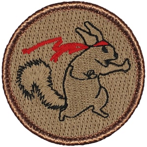 May include: A brown embroidered patch with a cartoon squirrel wearing a red headband and a red tail. The squirrel is in a fighting stance.