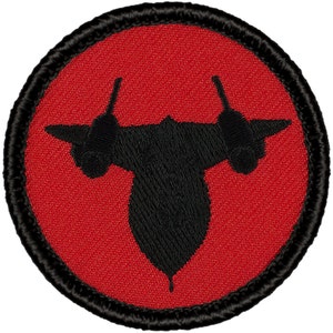 May include: A red and black embroidered patch with a silhouette of a SR-71 Blackbird aircraft.