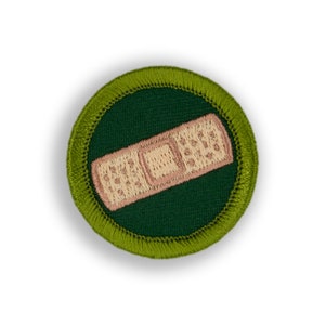 May include: A green and yellow embroidered patch with a white and pink bandage on a green background.