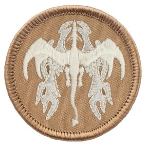May include: A circular embroidered patch featuring a stylized white dragon-like creature on a tan background. The patch has a tan border with detailed stitching. The design is symmetrical, with the creature's wings and limbs extending outwards.