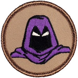May include: Purple and black embroidered patch of a hooded figure with a menacing expression. The patch is circular and has a brown border.