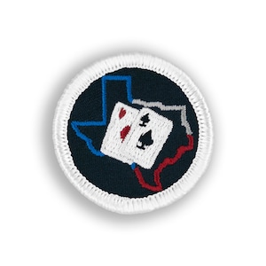 May include: A black and white embroidered patch featuring a stylized outline of the state of Texas with two playing cards, an ace of spades and an ace of hearts, inside the outline.