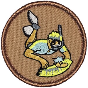 May include: A brown embroidered patch with a cartoon illustration of a person wearing a snorkel and diving into the water. The person is wearing a blue and yellow shirt and has a yellow beard.