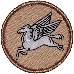 May include: A brown embroidered patch with a white winged horse design. The horse is running with its wings spread out.