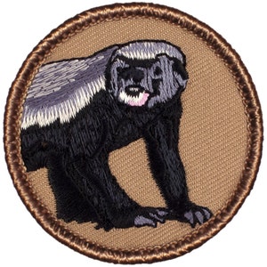 May include: Embroidered patch featuring a honey badger with black fur, a white stripe, and a gray face. The patch is circular and has a brown border.