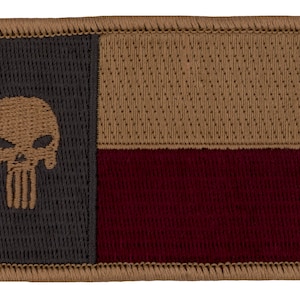 May include: A brown, black, and maroon embroidered patch featuring the Texas state flag with a stylized skull and crossbones in the upper left corner.