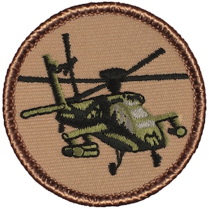 May include: A brown embroidered patch with a green and black helicopter on a tan background.