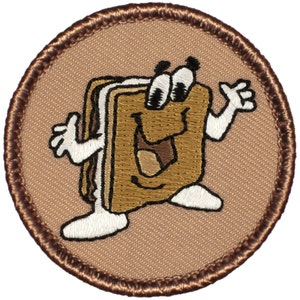 May include: A brown embroidered patch with a cartoon s'more character with a smiling face and googly eyes. The s'more is wearing white arms and legs and is waving with one hand.