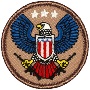 May include: A brown embroidered patch with a bald eagle holding two rifles. The eagle is holding a shield with red and white stripes and a blue field with white stars. The patch has a brown border.