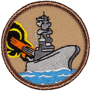 May include: A brown embroidered patch with a gray ship and a yellow and orange explosion. The ship is in the water, which is blue.