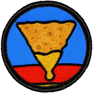 May include: A round, embroidered patch with a black border. The center of the patch is blue with a red stripe at the bottom. A yellow, cone-shaped object with a textured top is centered on the blue background.