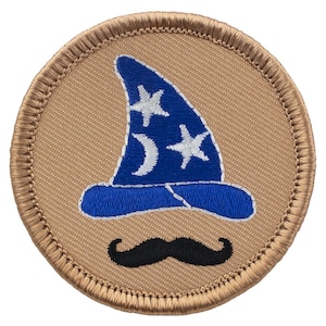 May include: A tan embroidered patch with a blue wizard hat with white stars and moons and a black mustache.