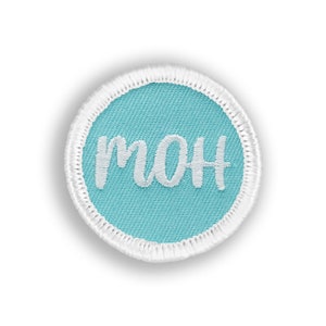 May include: A light blue round fabric patch with white stitching around the edge. The word "MOM" is embroidered in white on the patch.