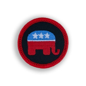 May include: A round patch featuring a red and blue elephant design with three white stars on a blue background. The elephant is red, and the patch has a red stitched border. The background is black.