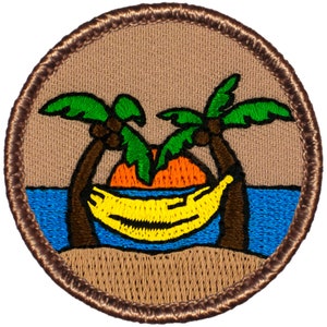 May include: A circular embroidered patch featuring a tropical beach scene with two brown palm trees, a bright orange sun, a blue ocean, and a yellow banana positioned in the foreground. The patch has a brown stitched border and a tan background.